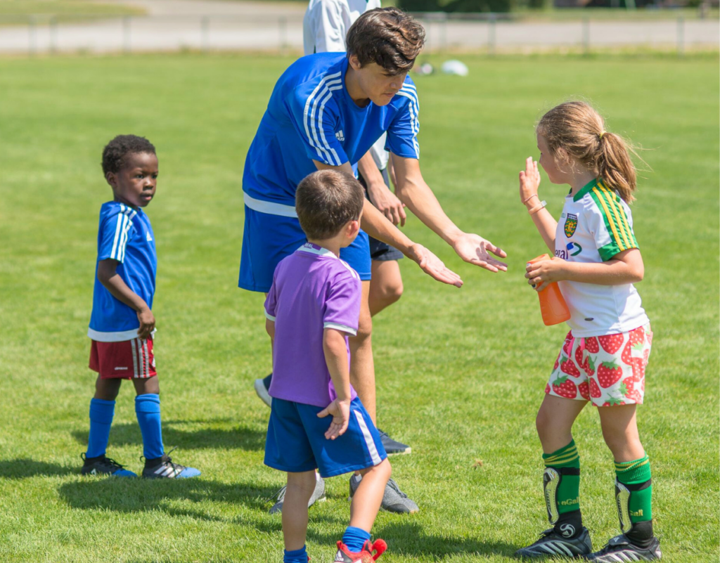 InterSoccer coach greeting a young girl during a Girls Only Soccer Course