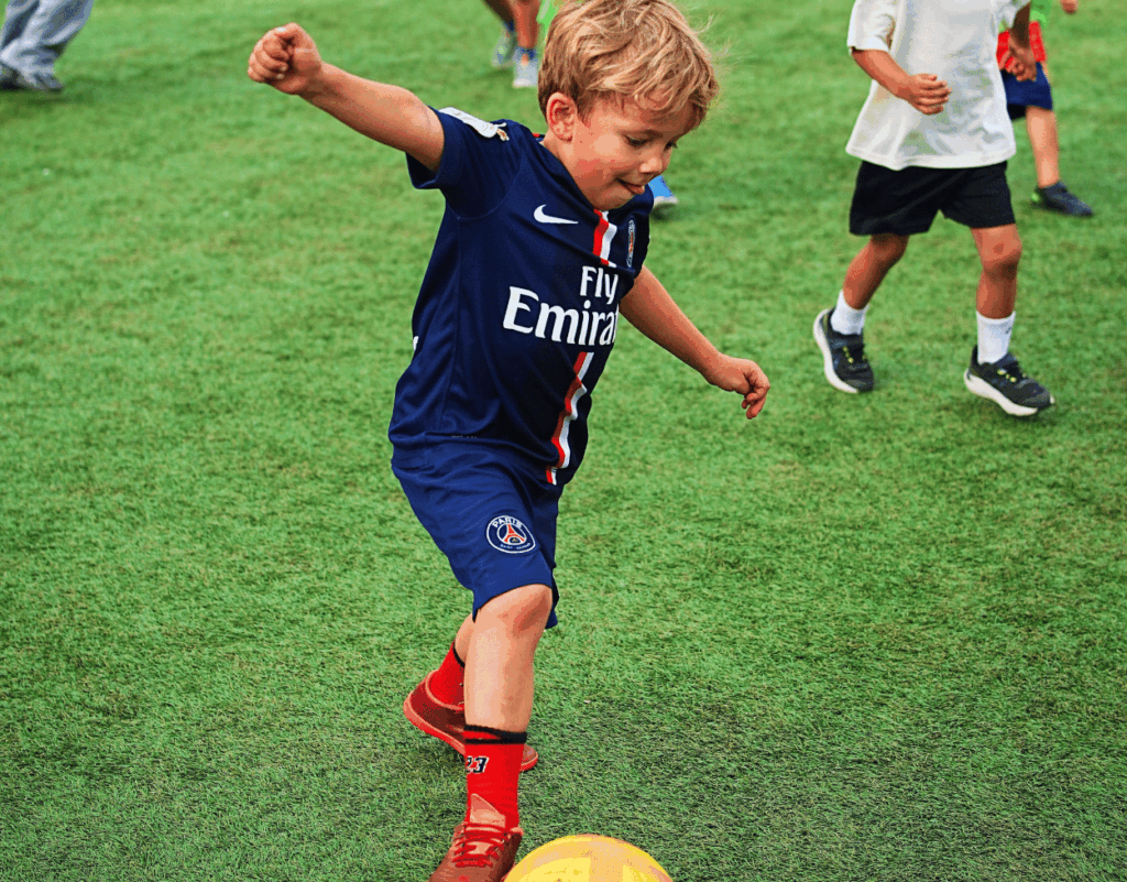 Young boy practicing football drills at an InterSoccer Autumn Camp